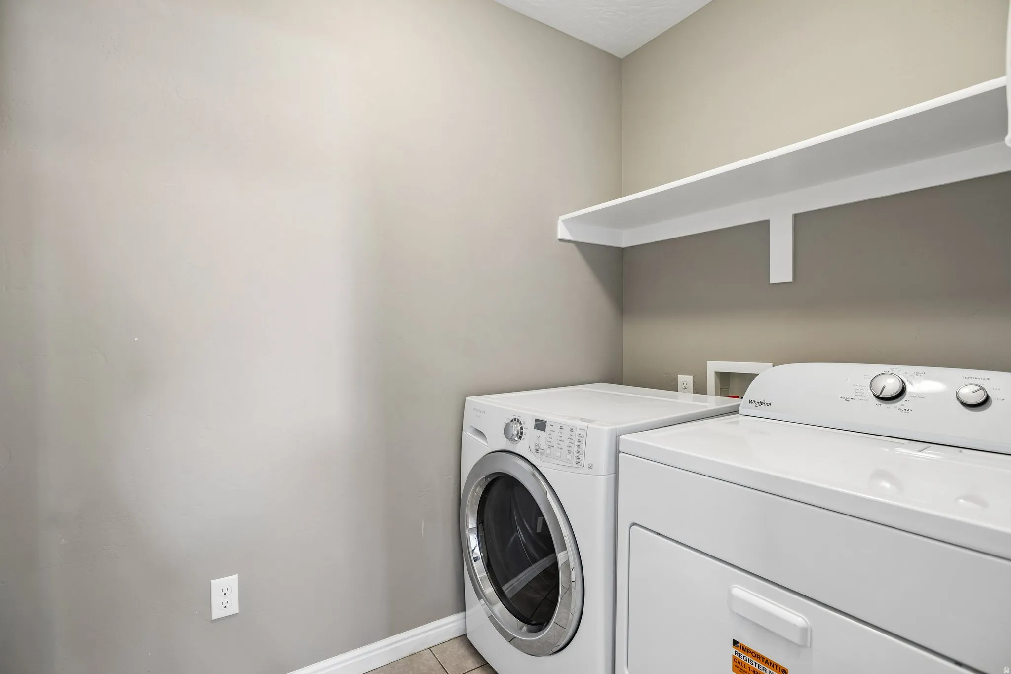 Dedicated laundry area featuring a built-in white shelf and tile flooring