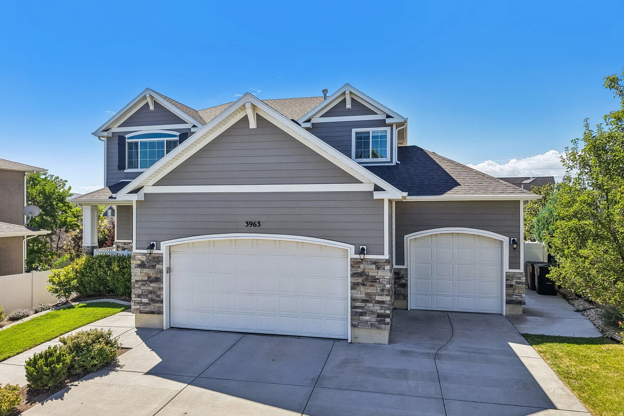 Two-story exterior with gray siding, stone accents, and a multi-car driveway