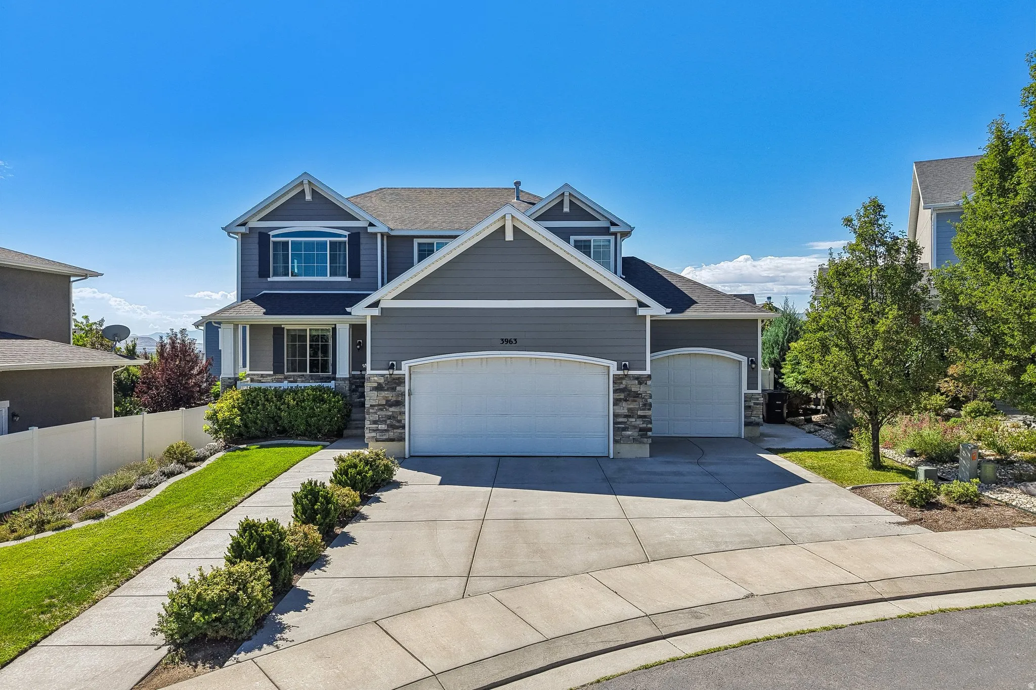 Contemporary two-story residence with a multi-gabled roofline, stone veneer accents, and a three-car garage
