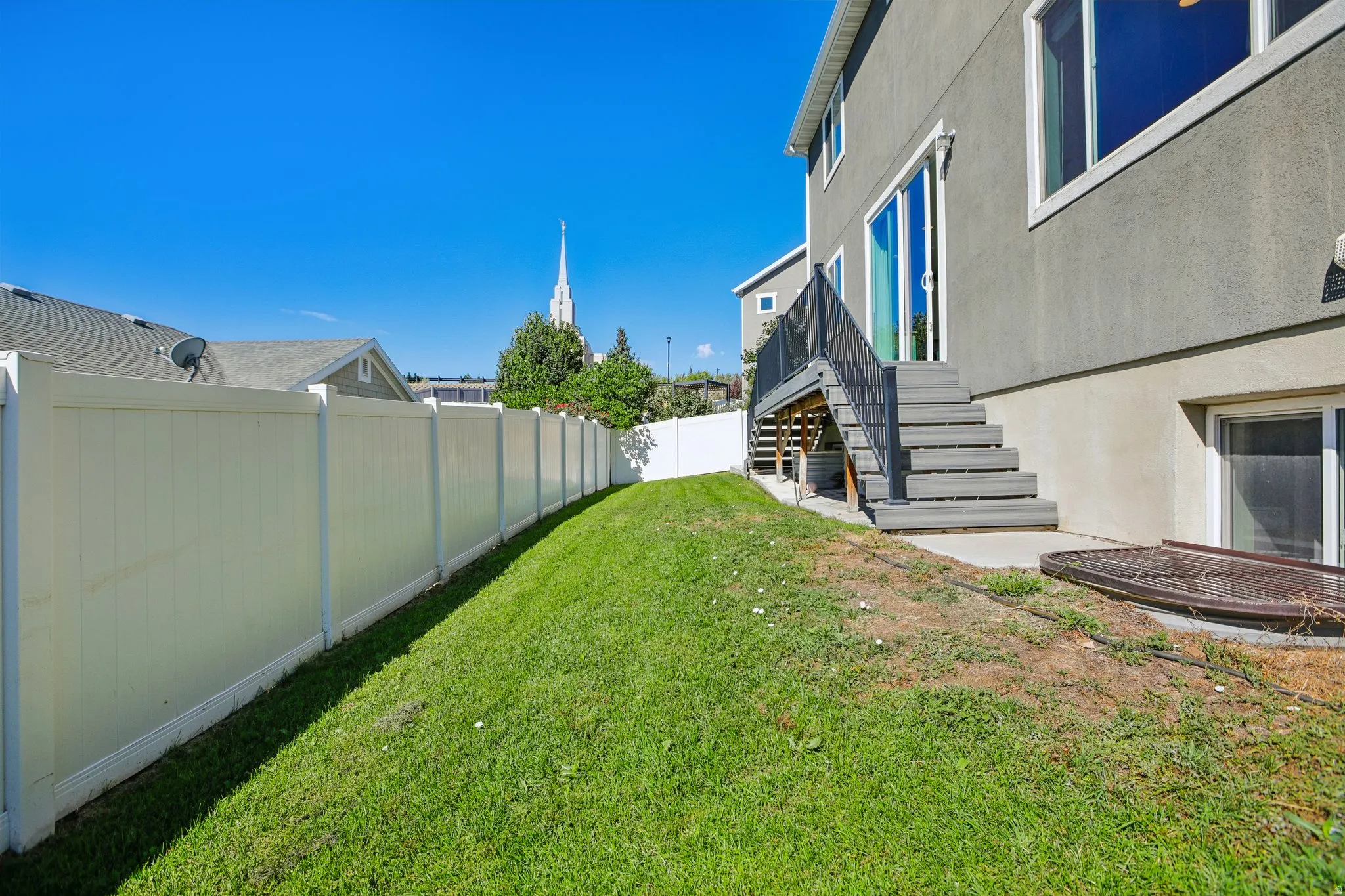 Expansive green lawn with a white privacy fence