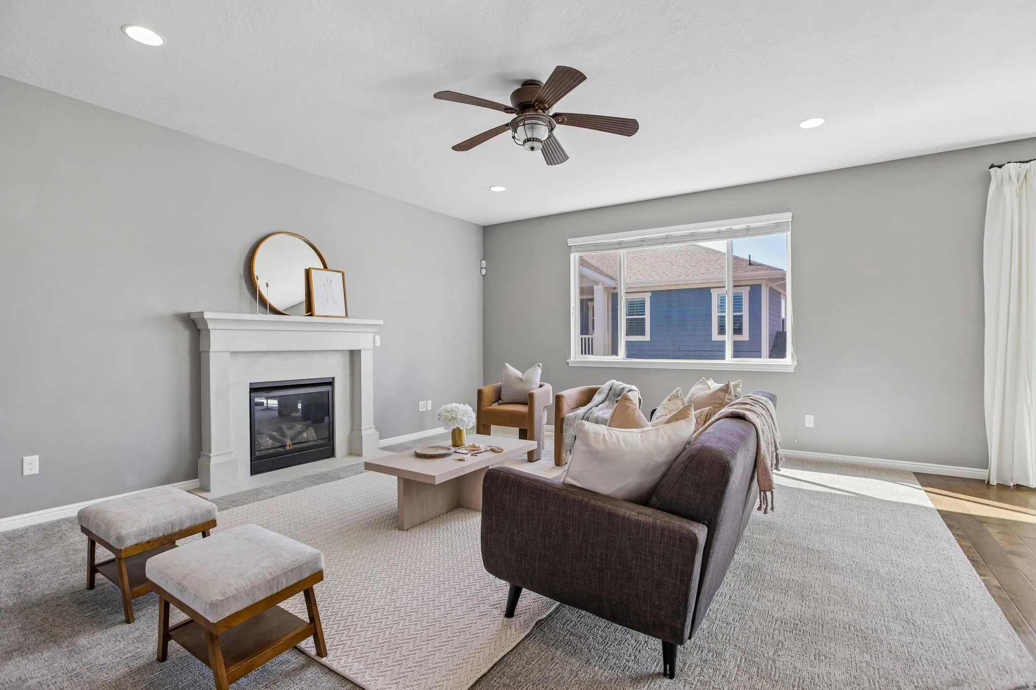 Recessed lighting, ceiling fan, fireplace with mantel, large window, and wood-finish flooring