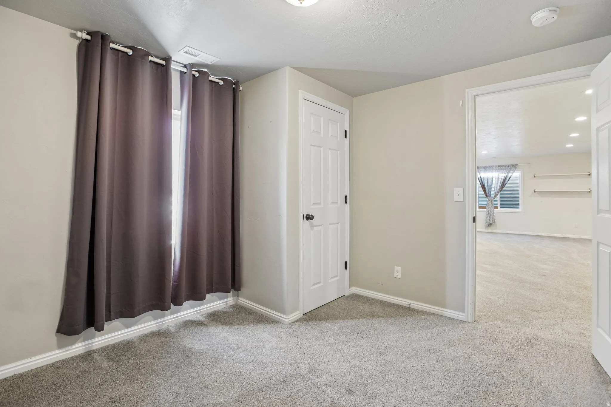 Neutral wall color, carpeted flooring, and a white interior door with black hardware