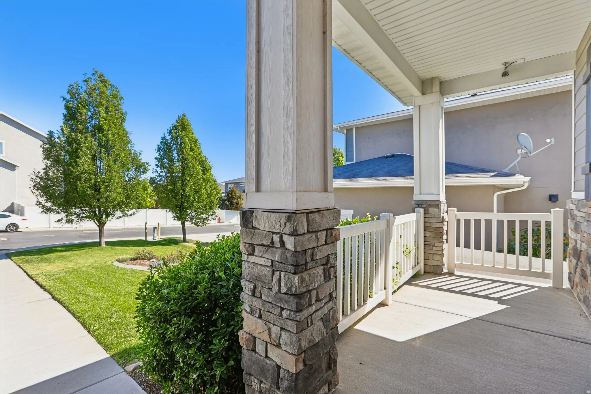 Covered concrete porch with stone-wrapped columns and white railing
