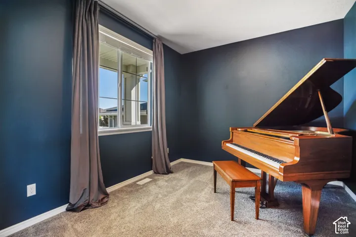 Dedicated music room featuring deep blue accent walls, large double-hung windows with gray drapery, neutral carpeting, and abundant natural light