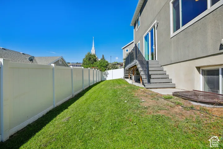 Expansive green lawn with a white privacy fence