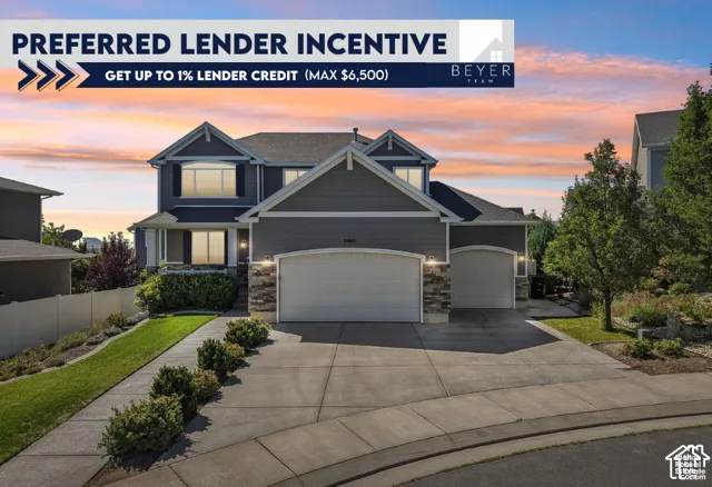 Two-story residence featuring horizontal lap siding, stacked stone accents, a concrete driveway, an attached three-car garage, and a landscaped front yard