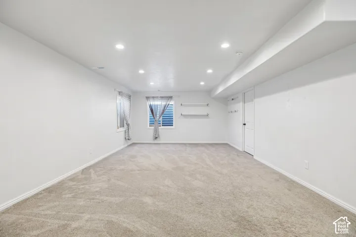Recessed lighting, light-toned carpeting, two windows with horizontal blinds, built-in shelving, and a panel door