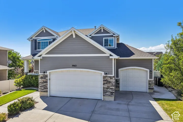 Two-story exterior with gray siding, stone accents, and a multi-car driveway