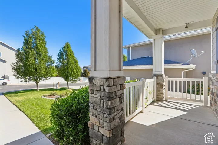 Covered concrete porch with stone-wrapped columns and white railing