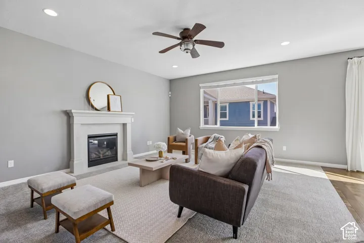 Recessed lighting, ceiling fan, fireplace with mantel, large window, and wood-finish flooring