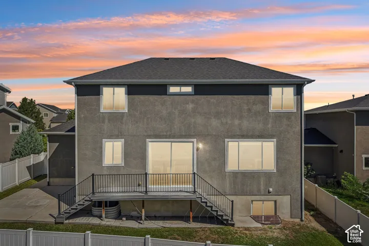Stucco exterior with multiple windows, a sliding glass door, and a black metal deck railing