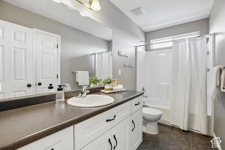 Full vanity mirror, white shaker-style cabinetry, dark countertop, single basin sink, and an integrated shower/tub unit