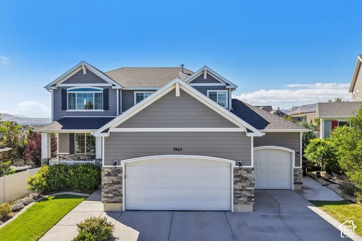 Two-story exterior with siding and stone accents, featuring a two-car garage, a single-car garage, and a covered front porch