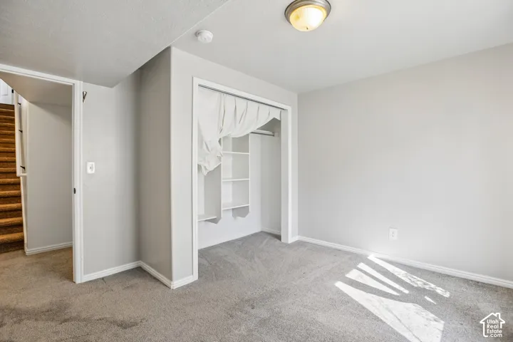 Carpeted flooring, built-in open shelving, surface-mounted ceiling light fixture, neutral wall color, and white trim