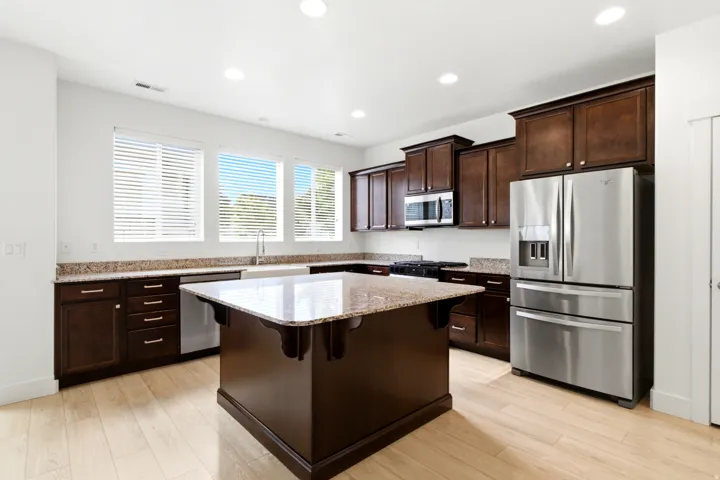 Kitchen featuring wood-finish flooring, dark wood cabinetry, and speckled countertops