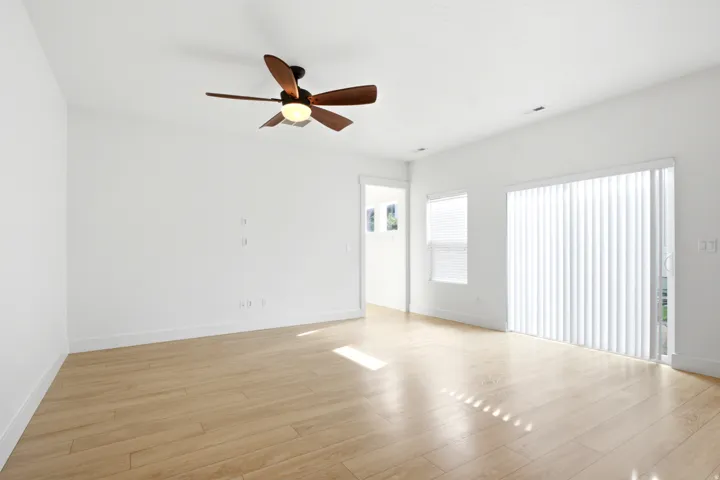 Wood-finish flooring, white walls, and a ceiling fan with integrated lighting