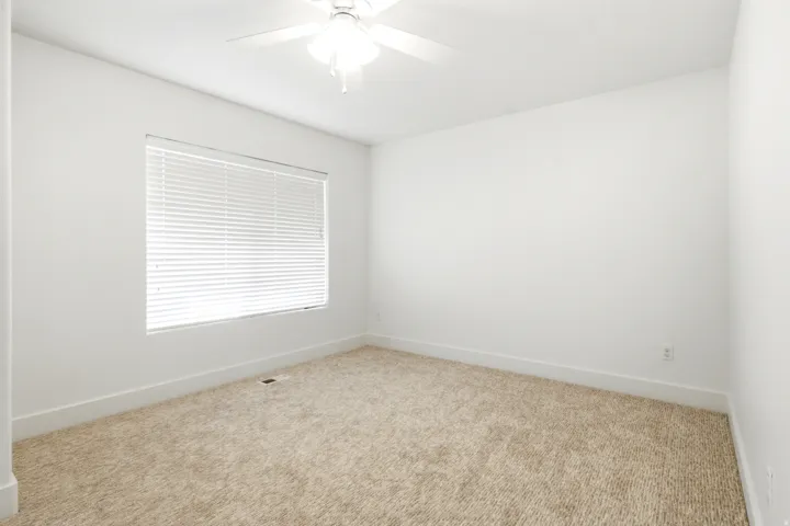 Recessed window with blinds, overhead ceiling fan, and light-colored carpeting