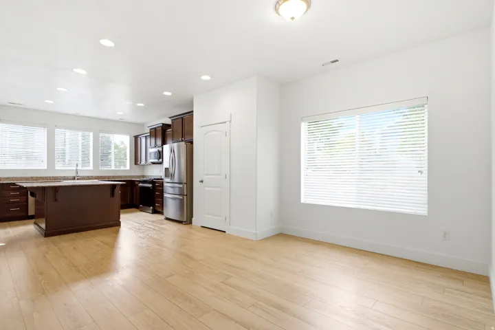 Open-concept layout with wood-finish flooring, dark wood cabinetry, and stainless steel appliances