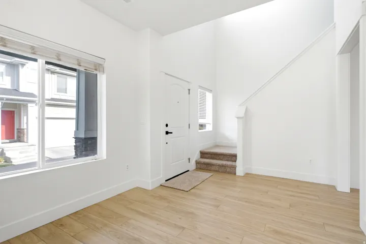 Bright entry with high ceilings, wood-finish flooring, a large window, and a carpeted staircase