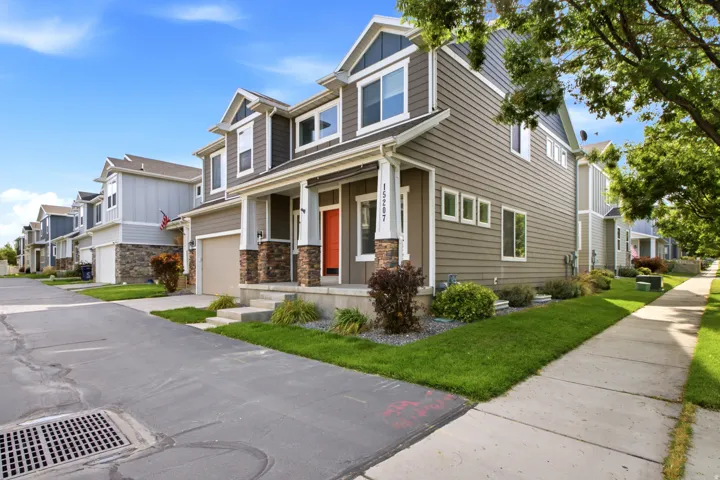 Multi-story residence featuring horizontal siding, stone veneer accents, an attached garage, and a covered front porch with columns