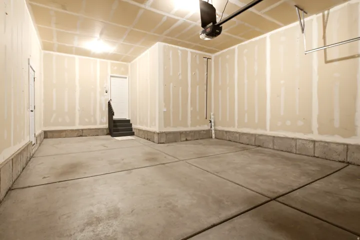 Concrete flooring with exposed drywall and an overhead garage door opener
