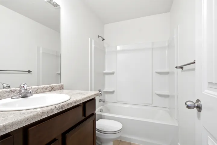 Bathroom featuring a vanity with a white oval sink, chrome faucet, and a stone-finish countertop