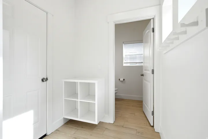 Light wood-finish flooring, white paneled doors, and a built-in storage cubby