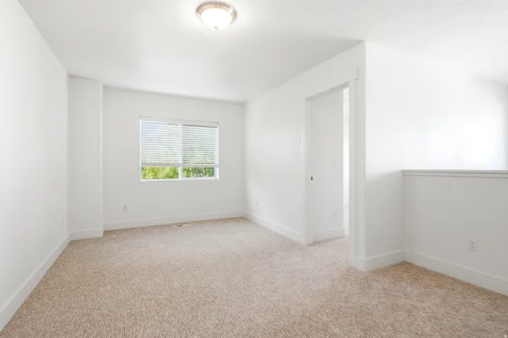 Carpeted room with a window, ceiling-mounted light fixture, and white painted walls