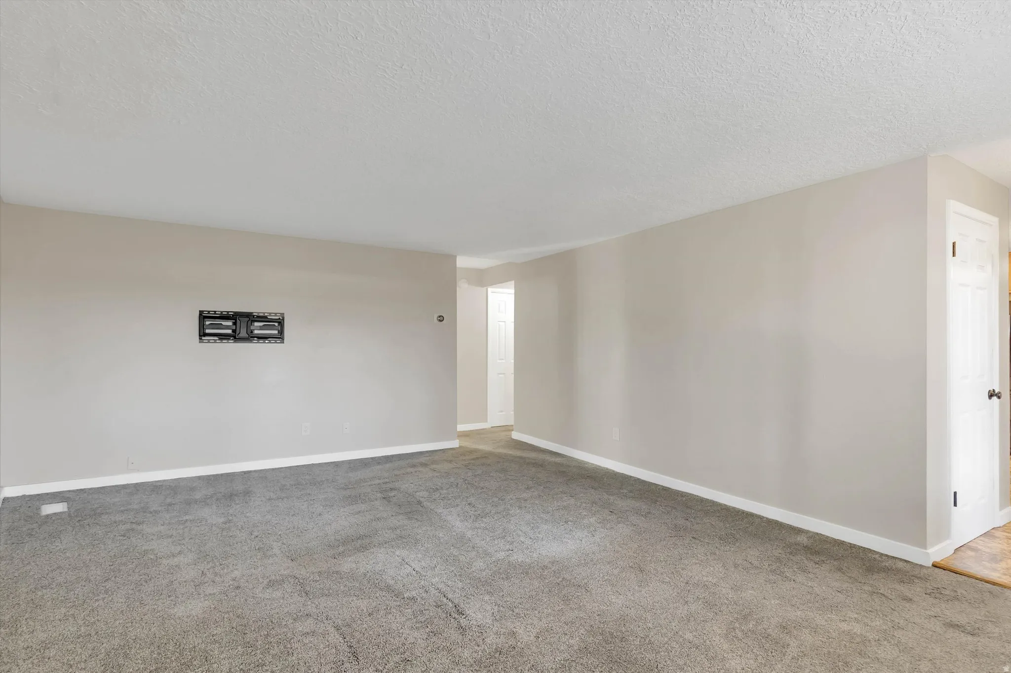 Wall-mounted television bracket, neutral wall color, and textured ceiling