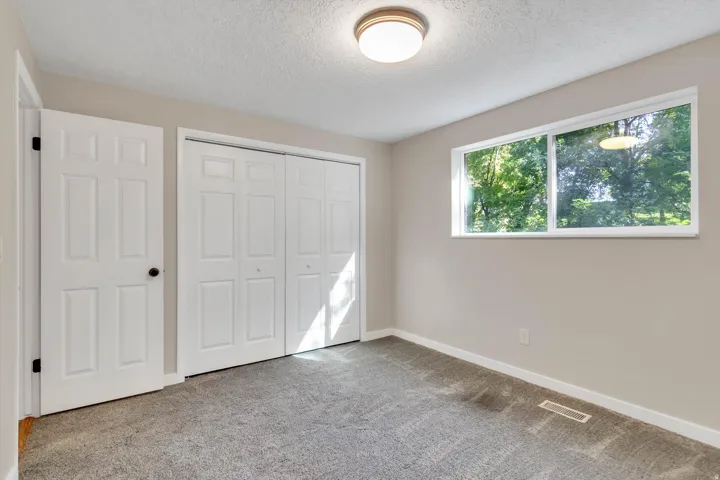 Light gray wall paint, textured ceiling, gray carpet, white trim, and a horizontal window