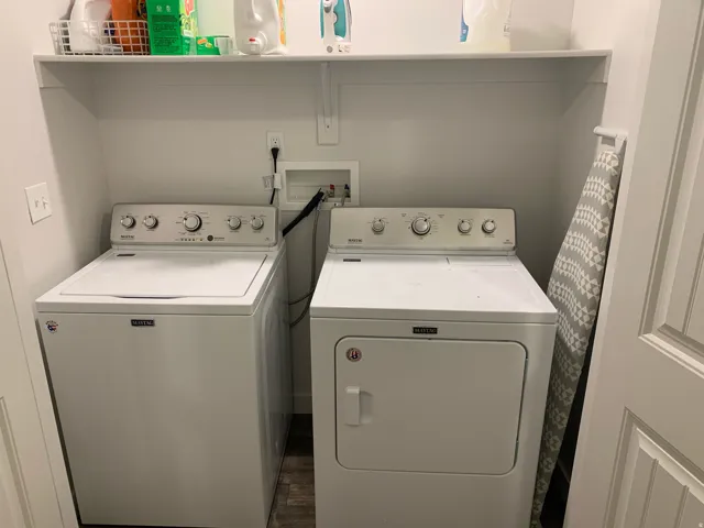Laundry area featuring white appliances, a built-in white shelf, and wood-finish flooring