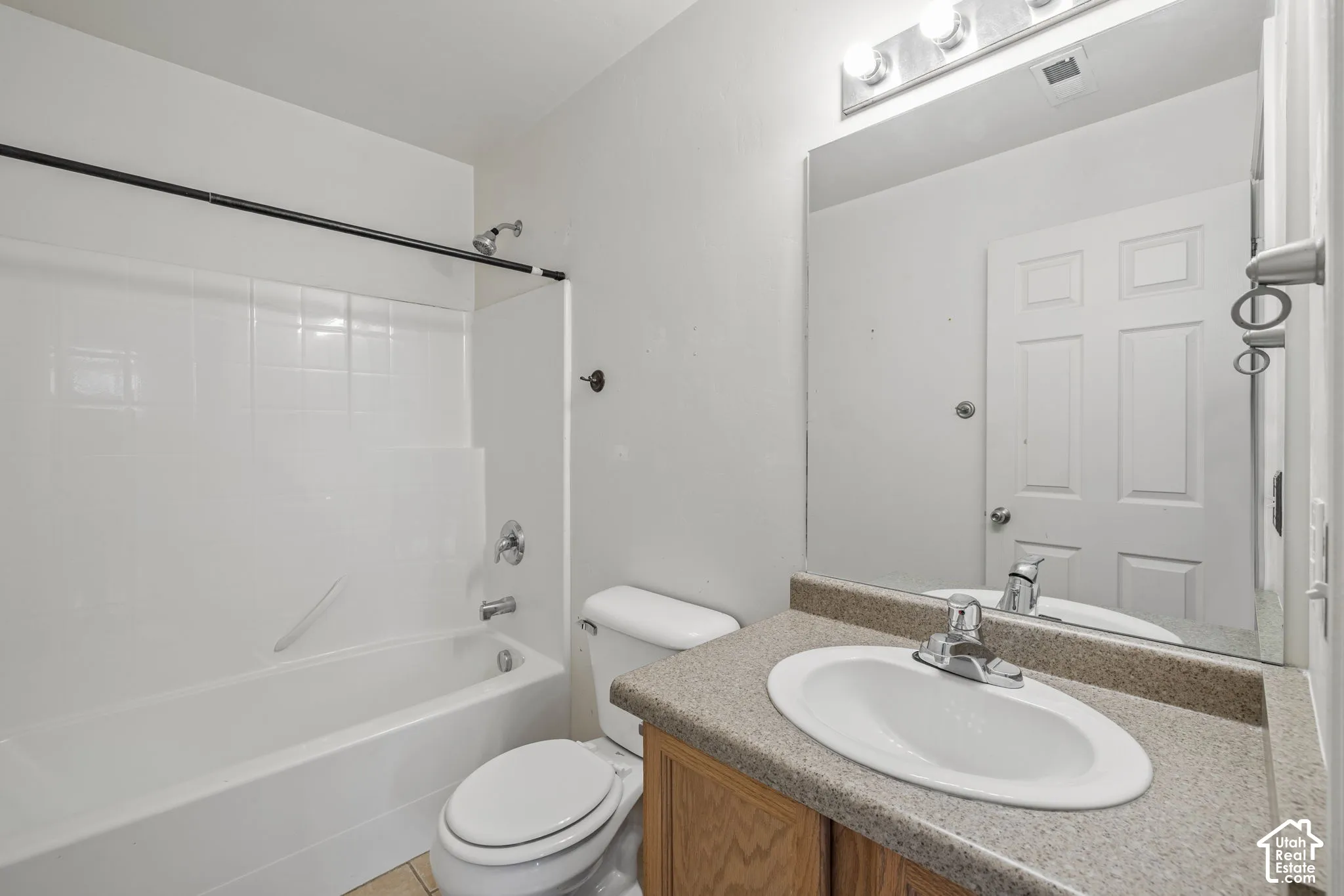 Full bathroom featuring a single vanity with an integrated sink, laminate countertop, and a shower-over-tub combination with a wall-mounted showerhead