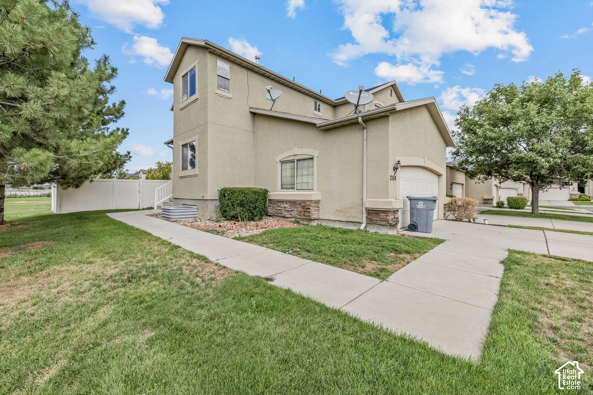 Stucco exterior with stone accents, a single-car garage, and a white picket fence