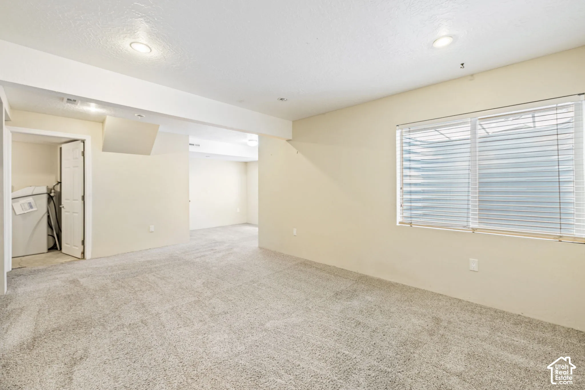Carpeted room with recessed lighting, a window with blinds, and light-colored walls