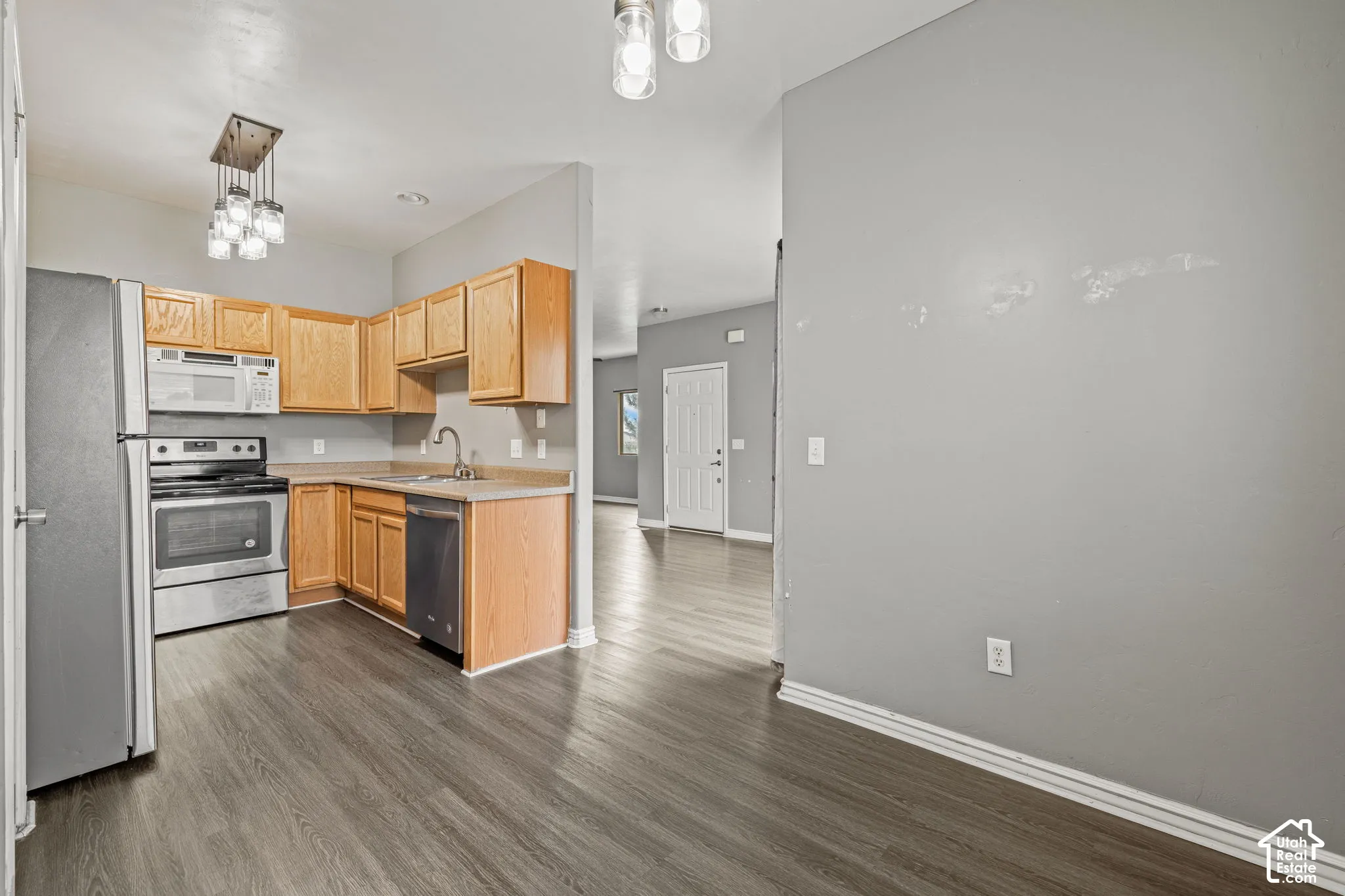Kitchen featuring wood-finish flooring, stainless steel appliances, wood cabinetry, and a double basin sink
