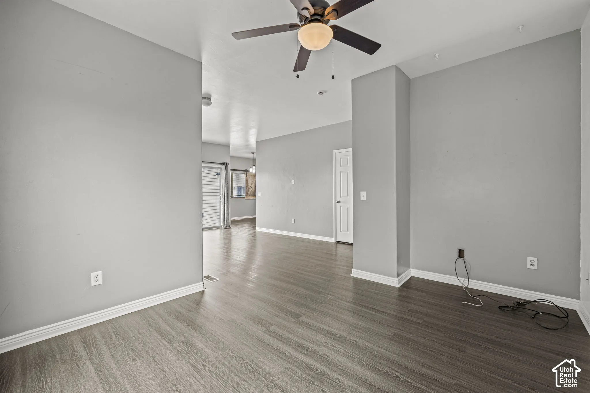 Wood-finish flooring, ceiling fan with integrated lighting, neutral wall tones, and white trim