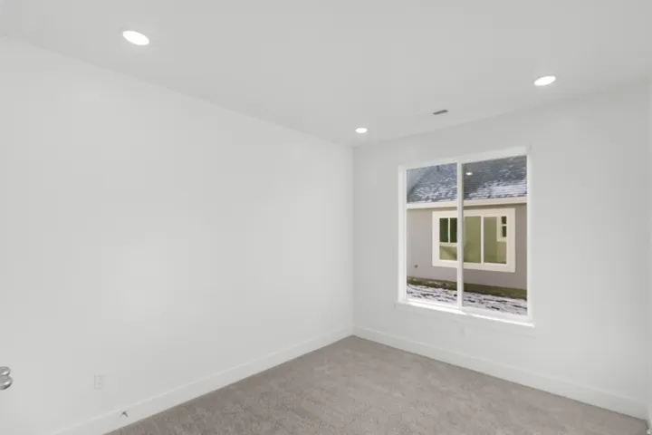 Recessed lighting, white walls, carpet flooring, and a large window