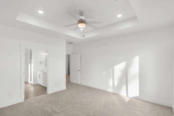 Recessed lighting, tray ceiling, ceiling fan with integrated lighting, broadloom carpeting, and a white paneled door