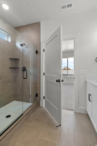 Walk-in shower with clear glass enclosure, neutral tile surround, and built-in shelving