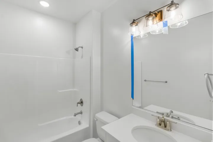 White vanity with integrated sink, brushed nickel faucet, and frameless mirror