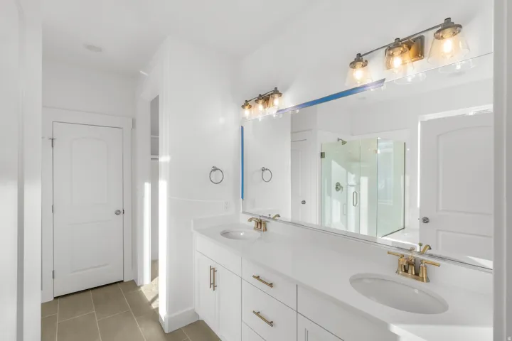 Dual vanity with white cabinetry, gold-finish hardware, and a white countertop