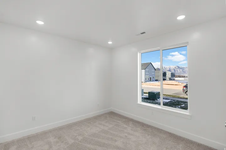Recessed lighting, large window, mountain scenery, light gray carpeting, and white walls