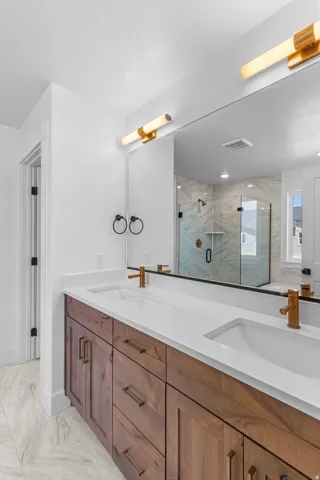 Dual vanity with integrated sinks, wood-finish cabinetry, and contemporary copper-tone fixtures