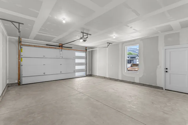 Spacious garage featuring a concrete floor, overhead lighting, and a window for natural illumination