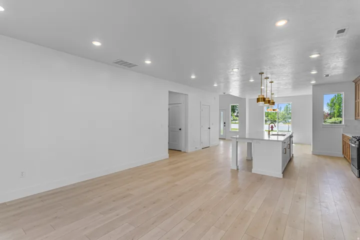 Recessed lighting, wood-finish flooring, kitchen island with seating, brass pendant lighting, and stainless steel range
