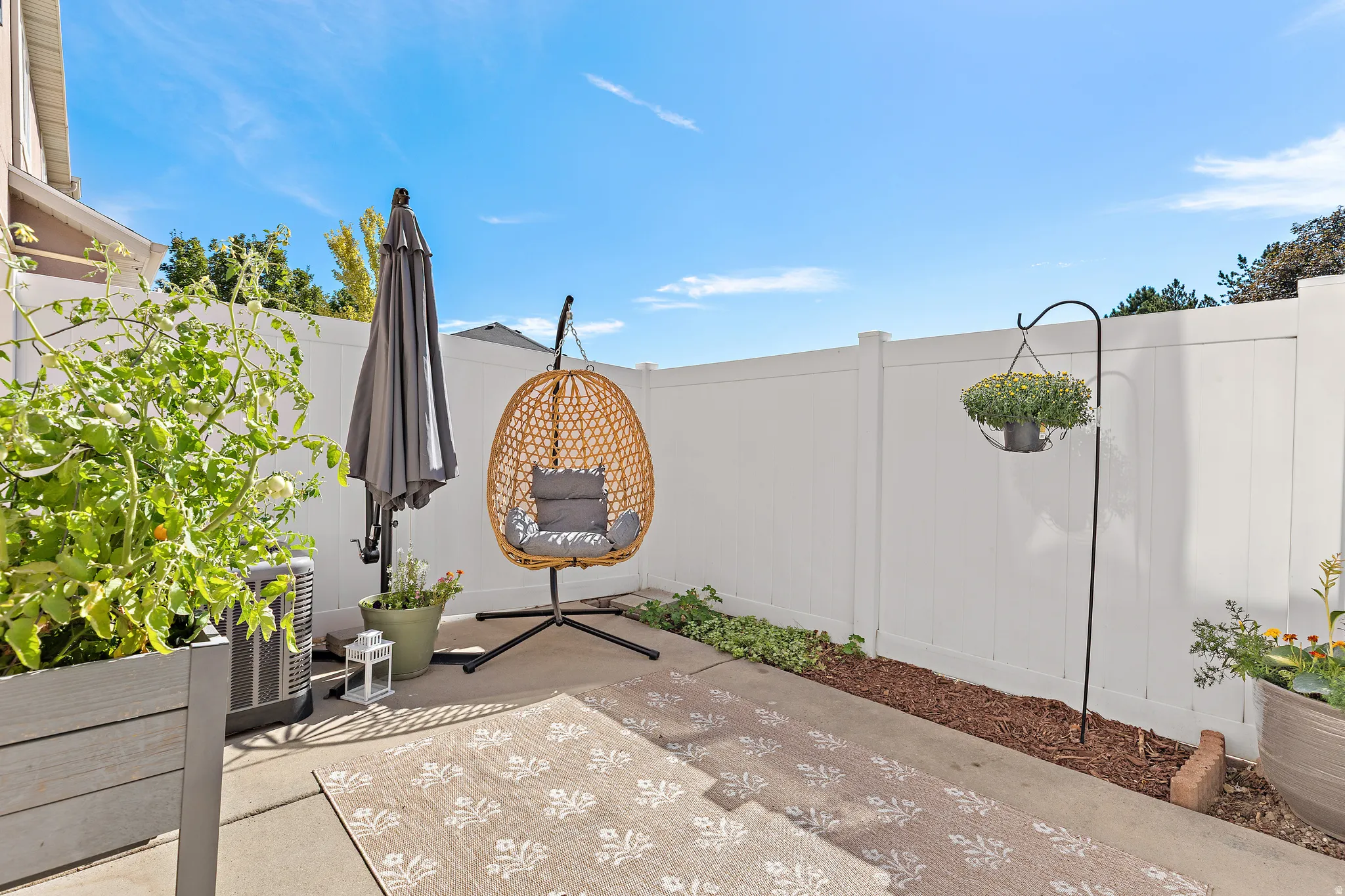 Spacious private patio featuring a white fence and flower bed