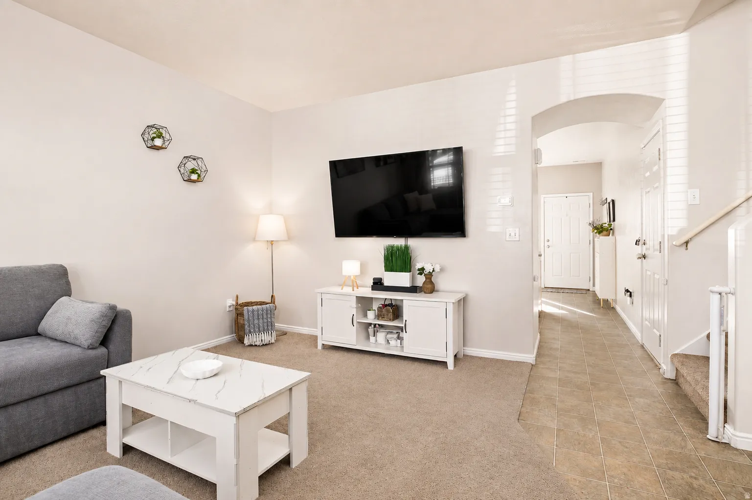 Bright spacious living area featuring carpeted flooring and multiple windows offering natural light with blinds