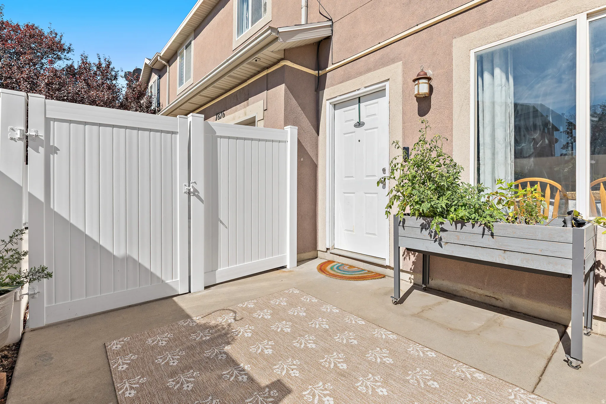 Spacious private patio featuring a white fence and flower bed