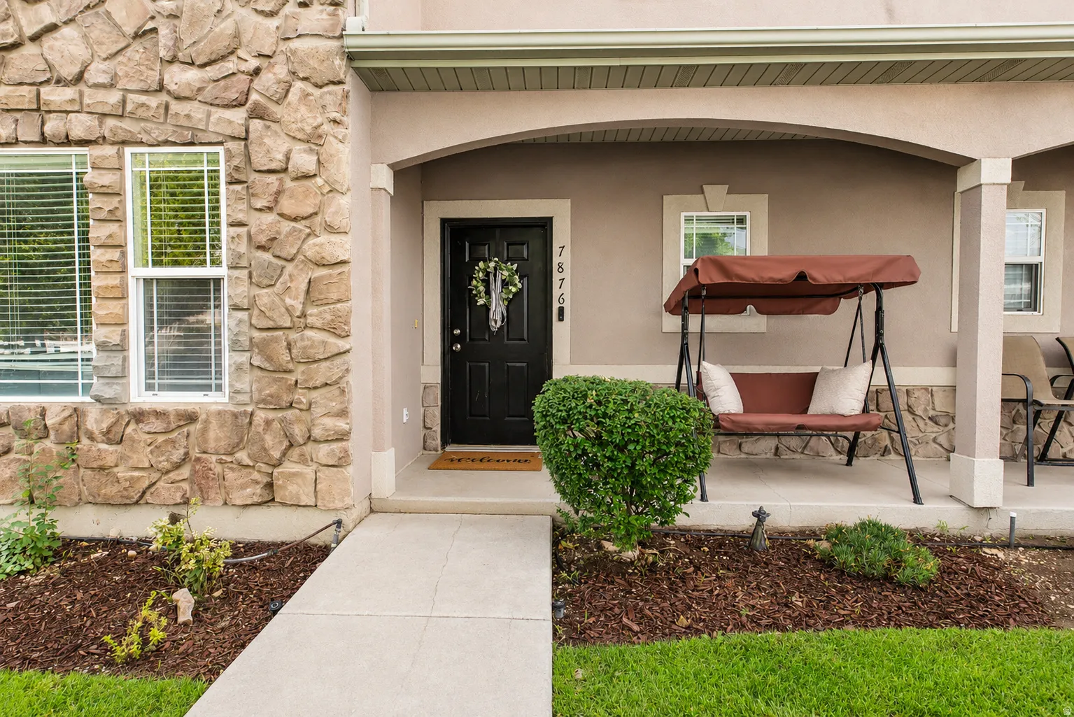 Stone veneer facade with multiple windows and a covered porch