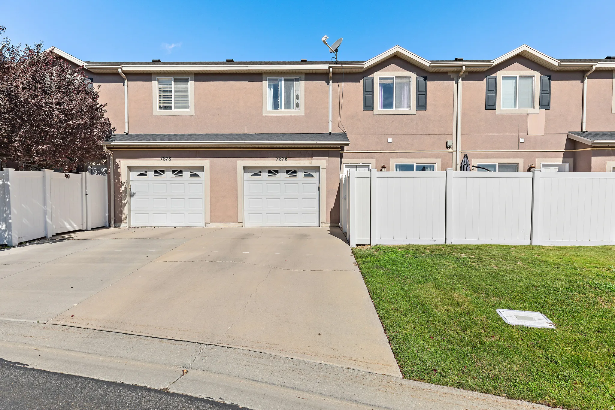 Attached one-car garage with gate to spacious private patio, vinyl fencing, manicured lawn, and dormer windows